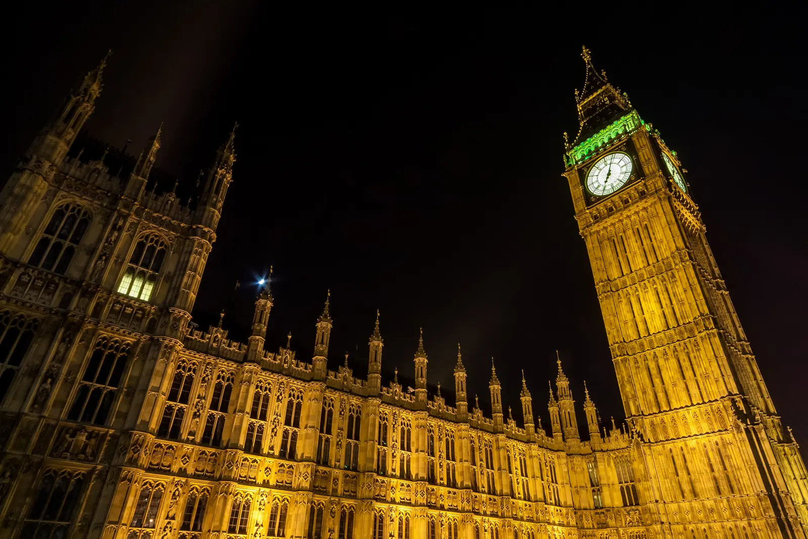 Elizabeth Tower (Big Ben) and the Palace of Westminster illuminated golden against the night sky in London, with dramatic upward perspective