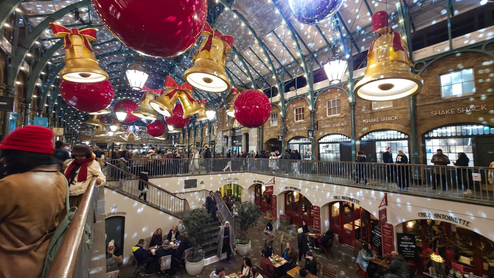 The historic Market Building of Covent Garden in London, showcasing its elegant iron-and-glass architecture and festive seasonal decorations within one of London's most vibrant public spaces