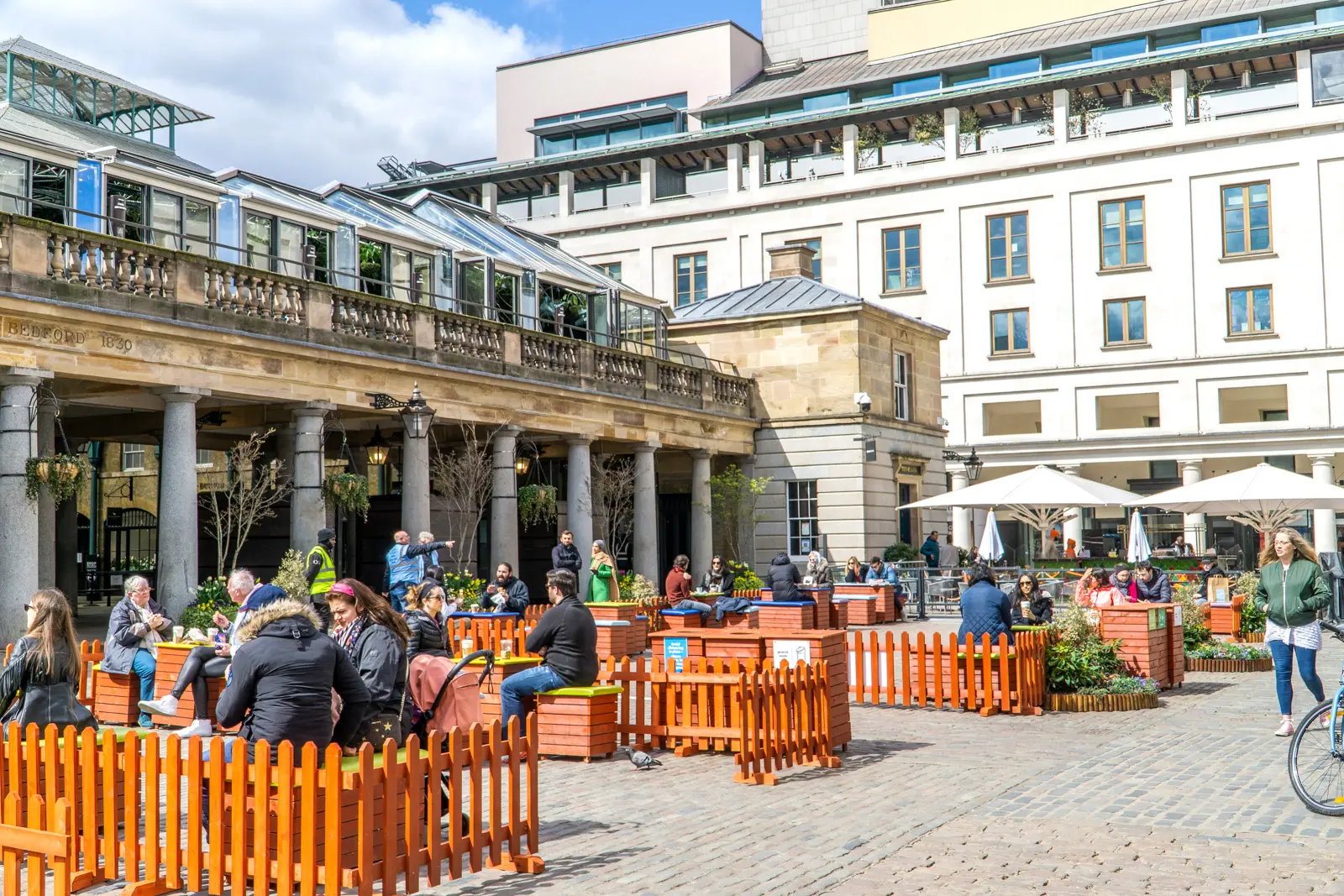 Visitors relaxing and enjoying the lively piazza of Covent Garden in London, surrounded by historic architecture, cafés, shops, and the vibrant atmosphere of one of London's most iconic public spaces
