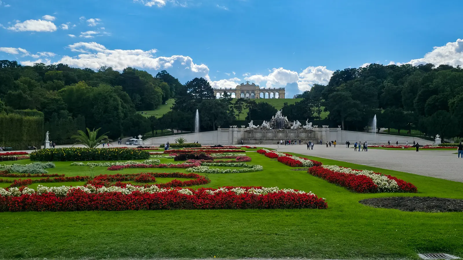 View across the Schönbrunn gardens with the Neptune Fountain and the Gloriette colonnade crowning the hill above the palace, Vienna
