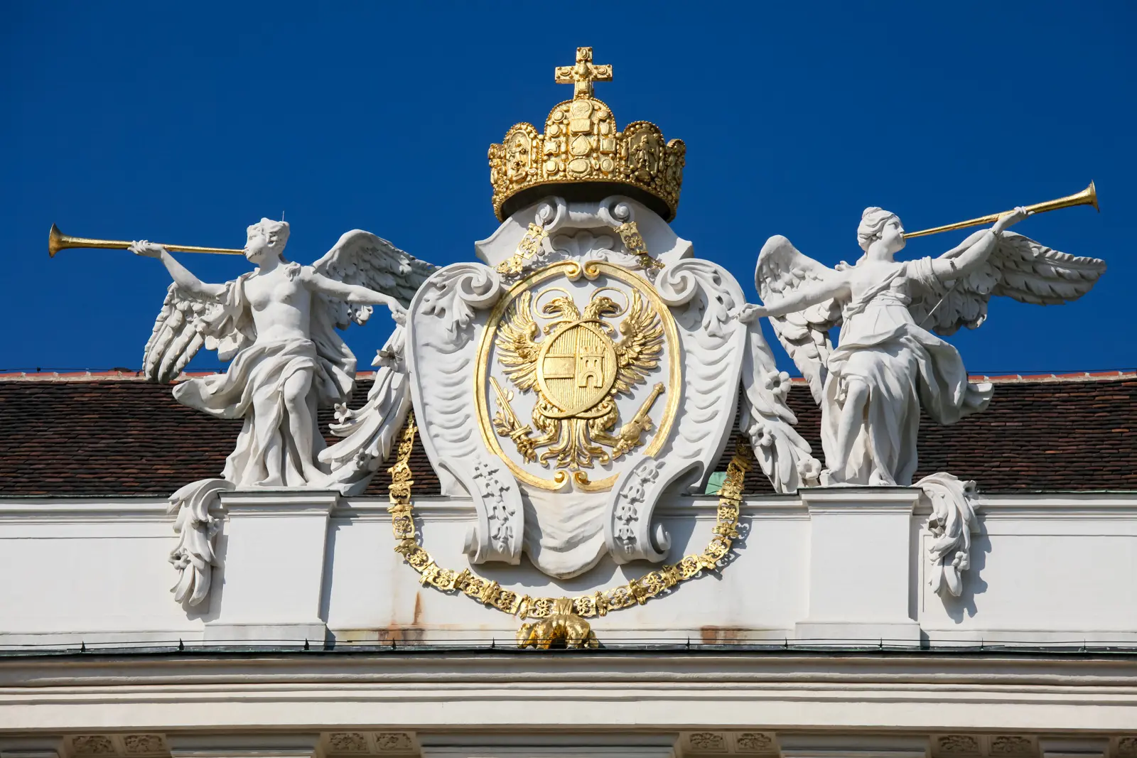 Habsburg imperial coat of arms with crowned double-headed eagle, trumpeting angels, and Order of the Golden Fleece collar atop St. Michael's Wing of Hofburg Palace in Vienna