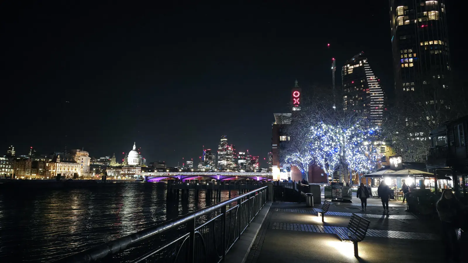 South Bank riverside at night looking west toward Blackfriars Bridge, St Paul's Cathedral, and the OXO Tower on the right. The tower was rebuilt in 1928–29 in Art Deco style by architect Albert Moore for the Liebig Extract of Meat Company; its O-X-O-shaped windows were a workaround for a contemporary ban on riverside skyline advertising, with the brand letters built into the architecture itself