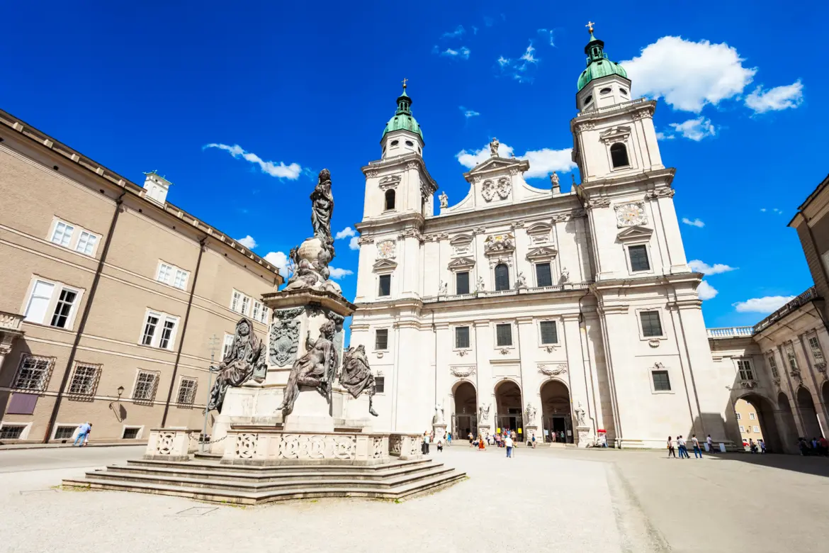 Domplatz with Salzburg Cathedral and the Mariensäule (Immaculate Column) at centre under blue sky and scattered clouds