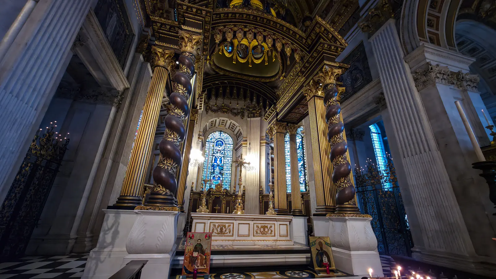 The high altar of St Paul's Cathedral with its 1958 gilded baldacchino, framed by four twisted columns modelled on Bernini's at St Peter's in Rome, with stained-glass apse windows visible behind