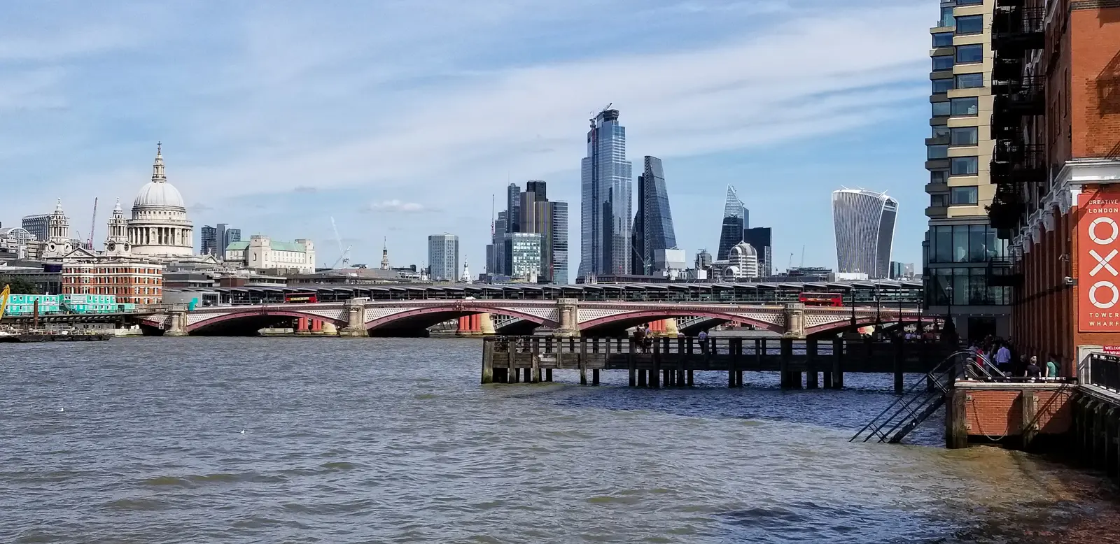 View of St Paul's Cathedral rising above the River Thames in London, with the modern financial district skyline surrounding one of the city's most historic landmarks