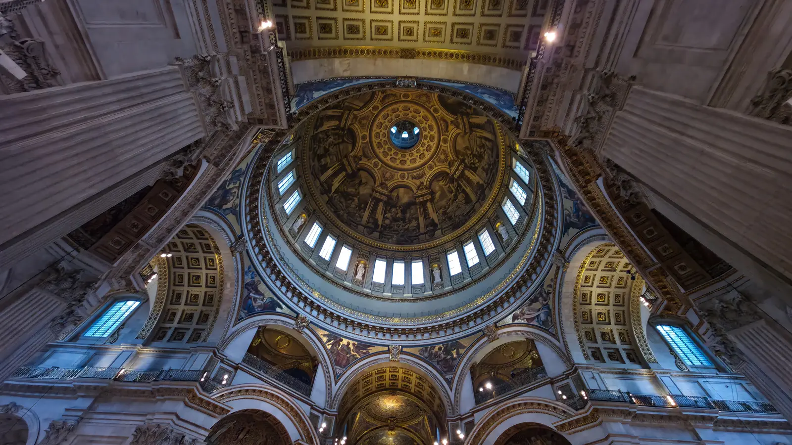 Interior view of the dome at St Paul's Cathedral looking straight up, showing Sir James Thornhill's eight monochromatic scenes from the life of St Paul, the oculus at the apex, and the supporting pendentives