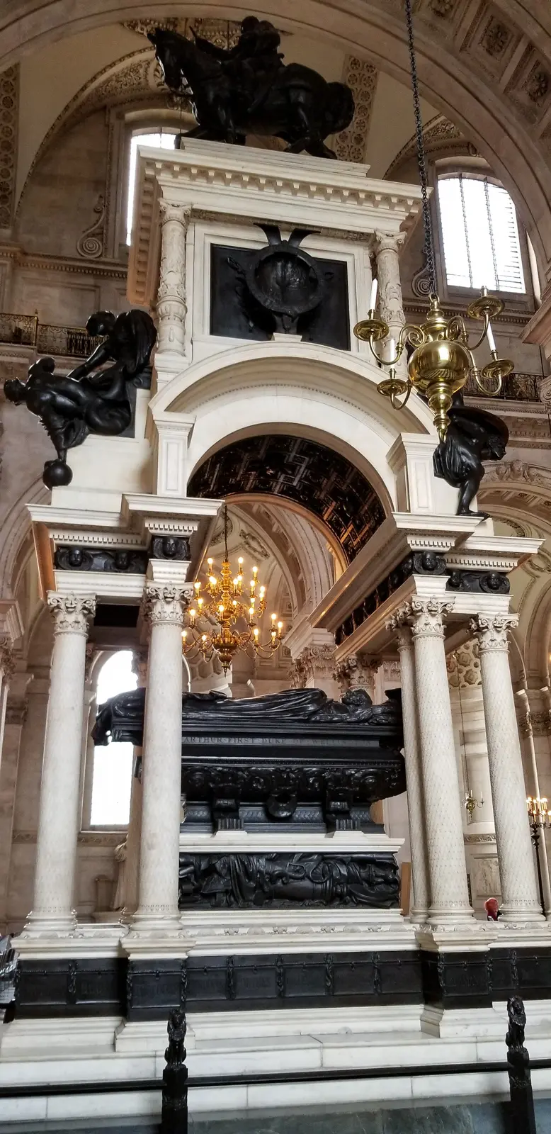 The Wellington Memorial in the north nave of St Paul's Cathedral, showing the bronze recumbent effigy of the Duke on a sarcophagus beneath a Triumphal-arch canopy, with the equestrian figure of Wellington on horseback mounted on top