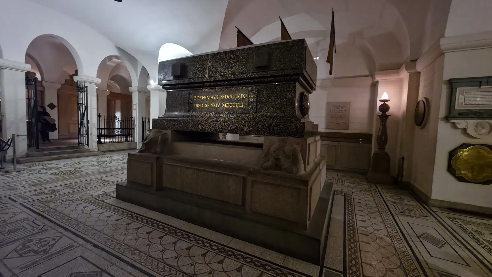 The Duke of Wellington's Cornish porphyry sarcophagus in the crypt of St Paul's Cathedral, inscribed with his birth and death dates in Roman numerals, resting on a Peterhead granite plinth carved with four sleeping lions
