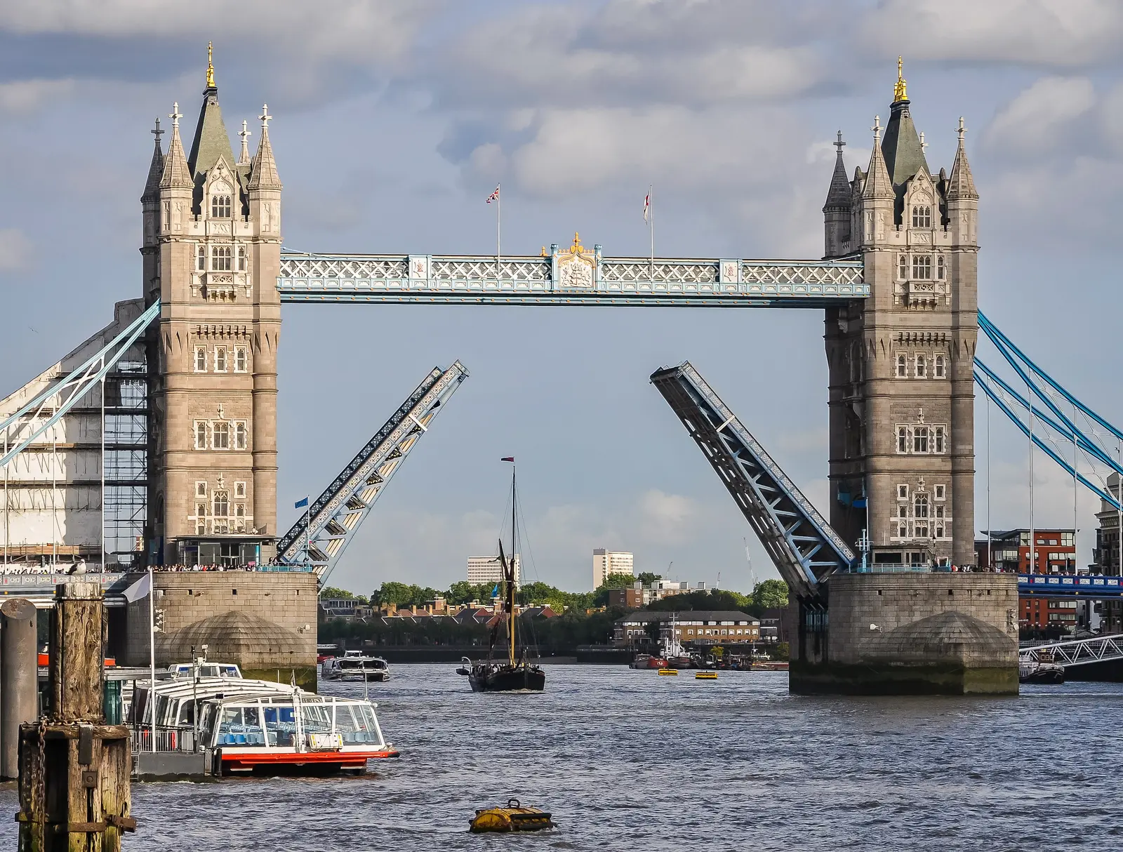 The raised bascules of Tower Bridge opening above the River Thames in London to allow a vessel to pass beneath, showcasing one of London's most iconic Victorian engineering spectacles