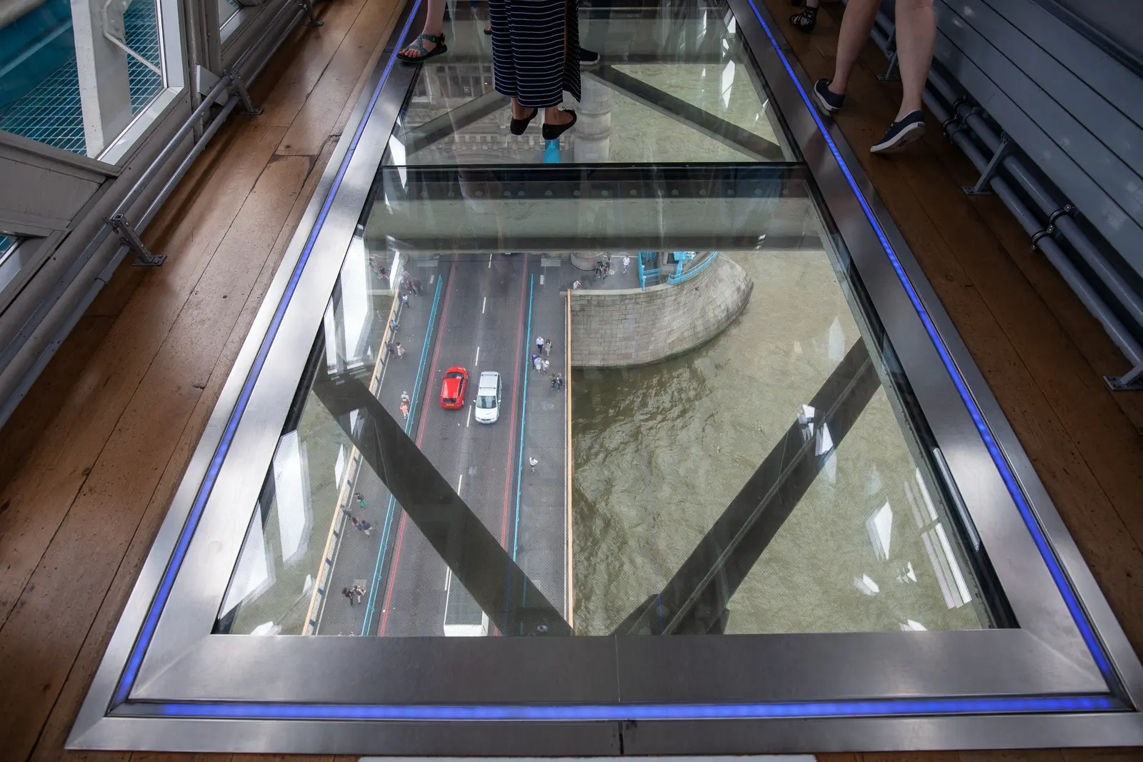 Glass floor walkway inside the Tower Bridge Exhibition in London, offering dramatic views above the traffic, pedestrians, and the River Thames below