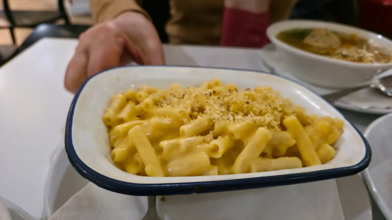 A blue-rimmed enamel dish of macaroni cheese topped with breadcrumbs at the Brass Rail in Selfridges