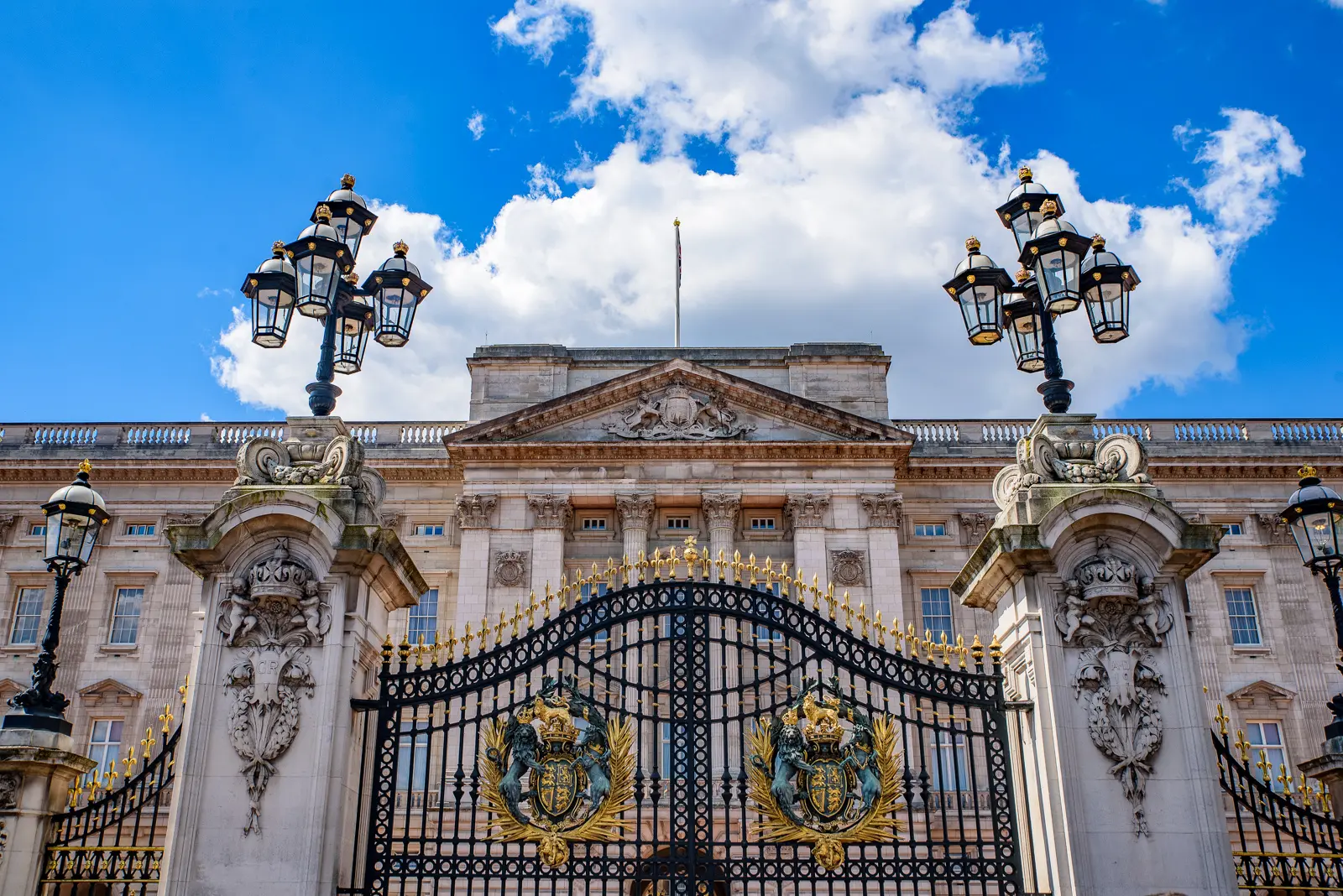 Close view of Buckingham Palace's main gates and central front beneath ornate lampstands