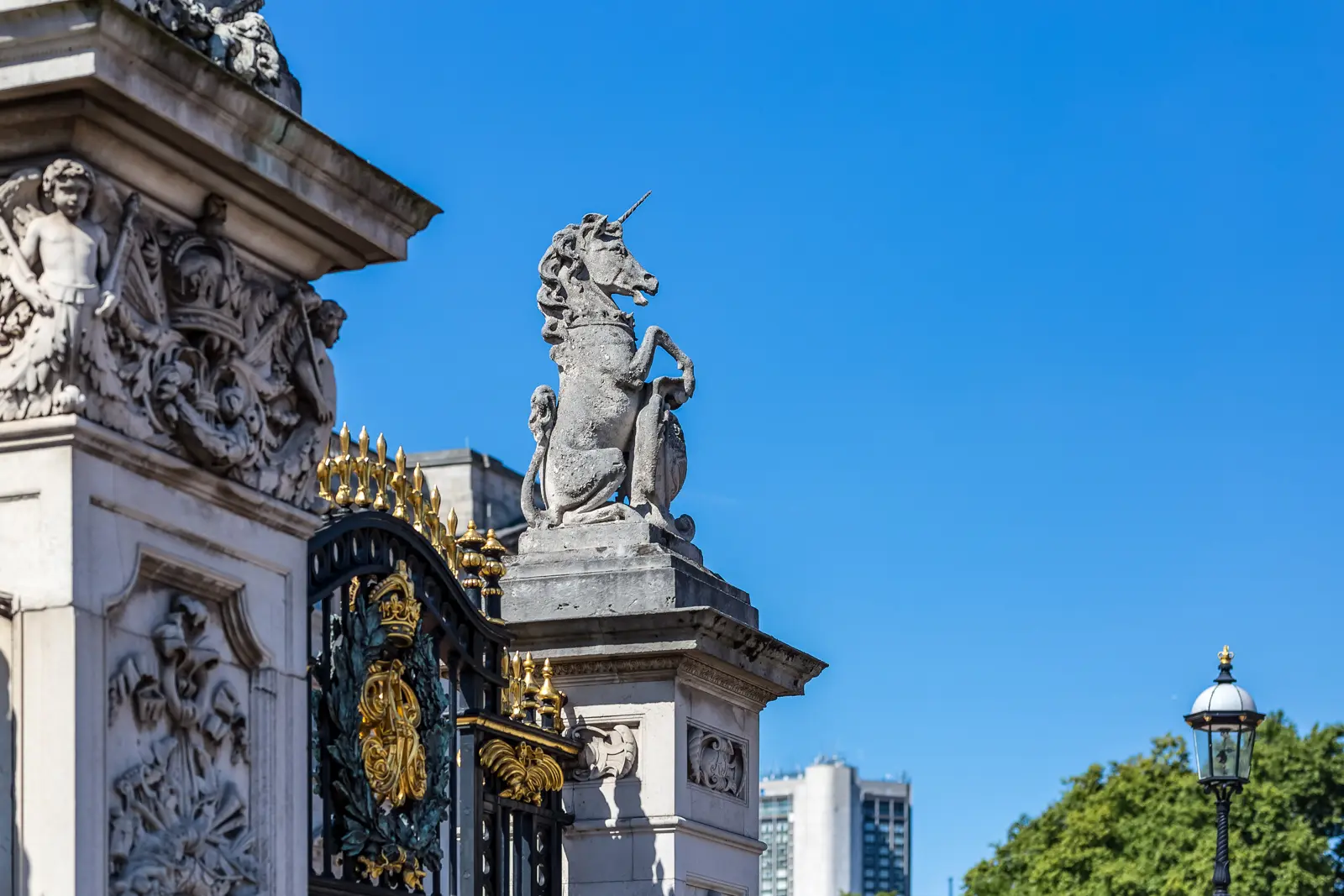 Stone unicorn rearing on a Buckingham Palace gate pier against a blue sky