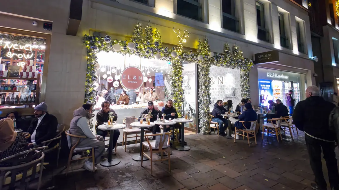 EL&N London's Hans Crescent café lit up at night beside Harrods, with Christmas garlands and pavement tables
