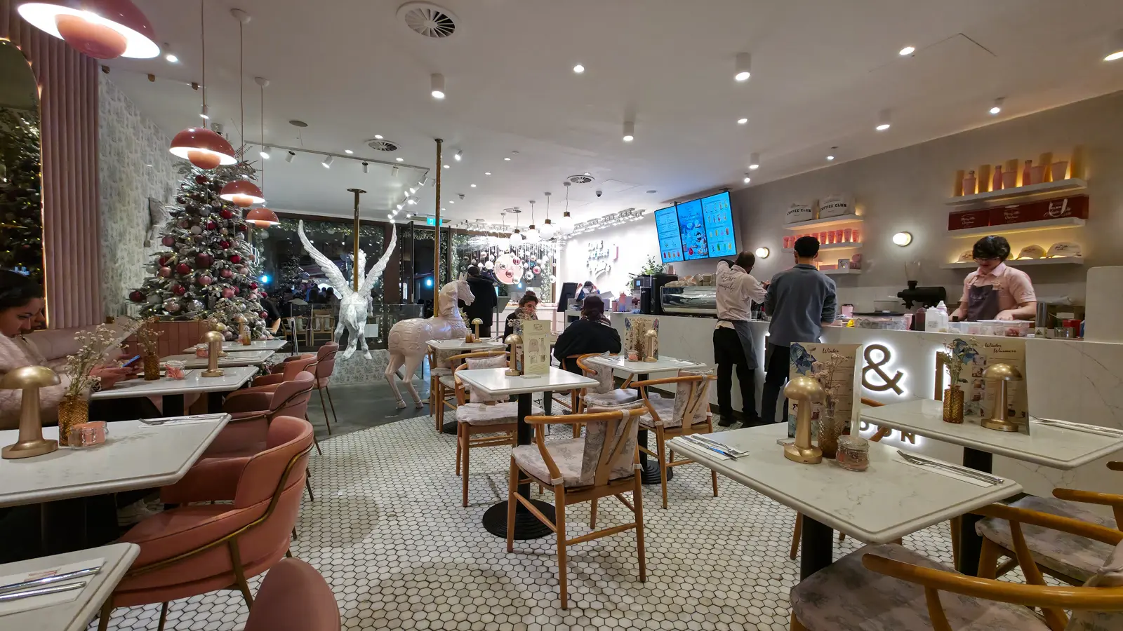 Pink chairs, marble tables and a flocked Christmas tree inside EL&N London Knightsbridge, with the white Pegasus statue