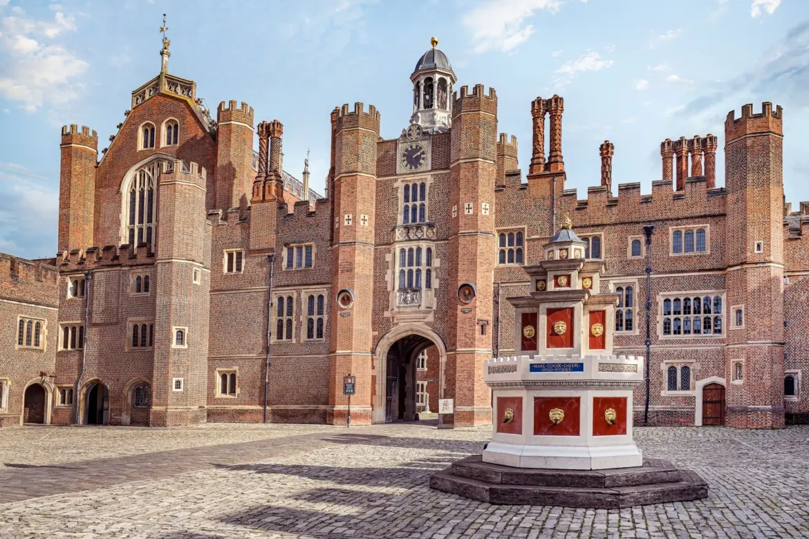 Base Court at Hampton Court Palace, the gilded red-and-gold Tudor wine fountain in front of the great red-brick gatehouse and clock tower