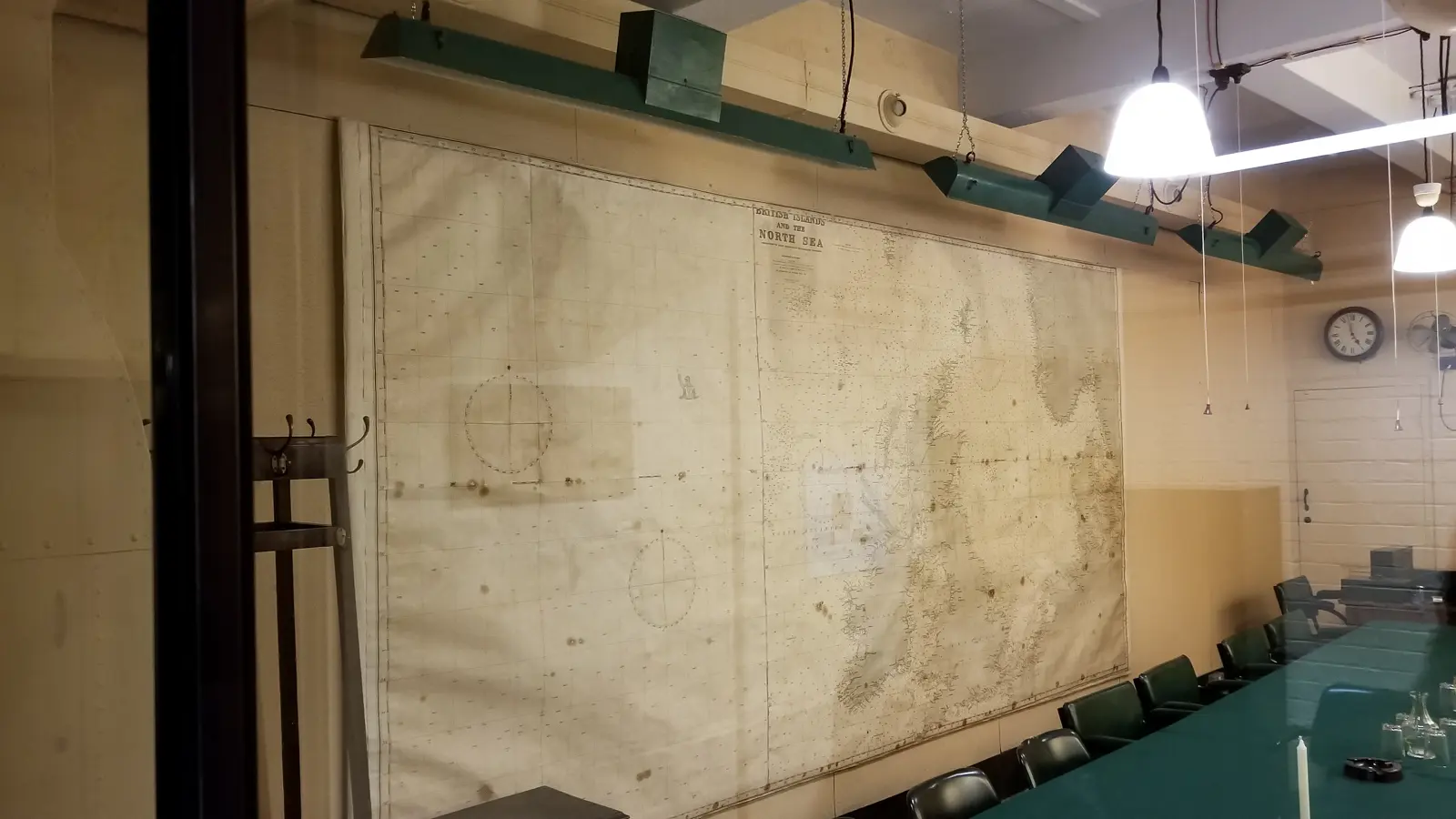 A chart-lined room in the Churchill War Rooms, London, with green-shaded lamps and a long table, kept as it was