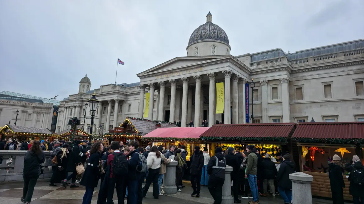 The National Gallery's domed portico rising above the wooden Christmas market chalets on Trafalgar Square, London, in December.