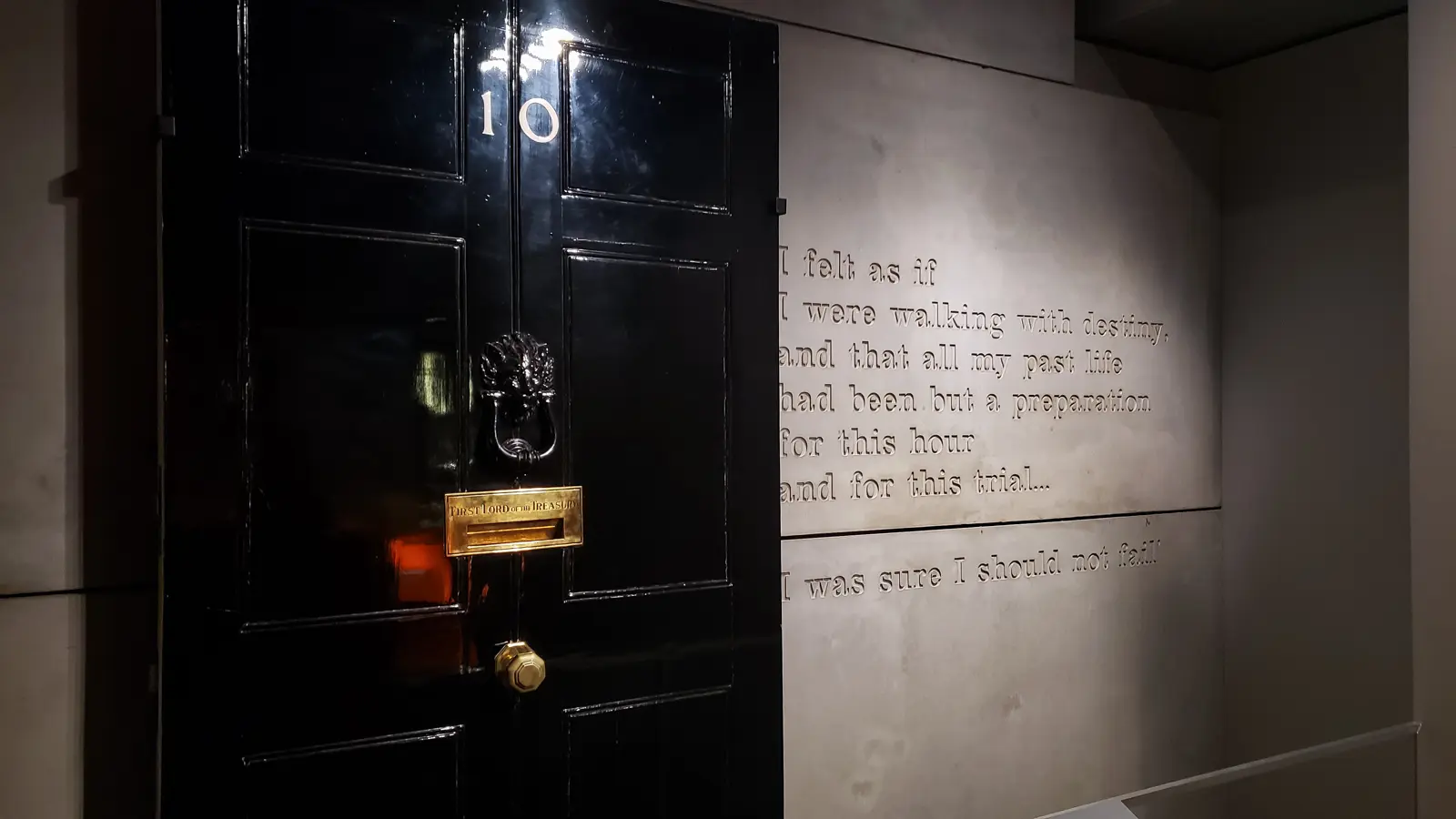 A replica of the No. 10 Downing Street door at the Churchill War Rooms, London, beside an engraved Churchill quote