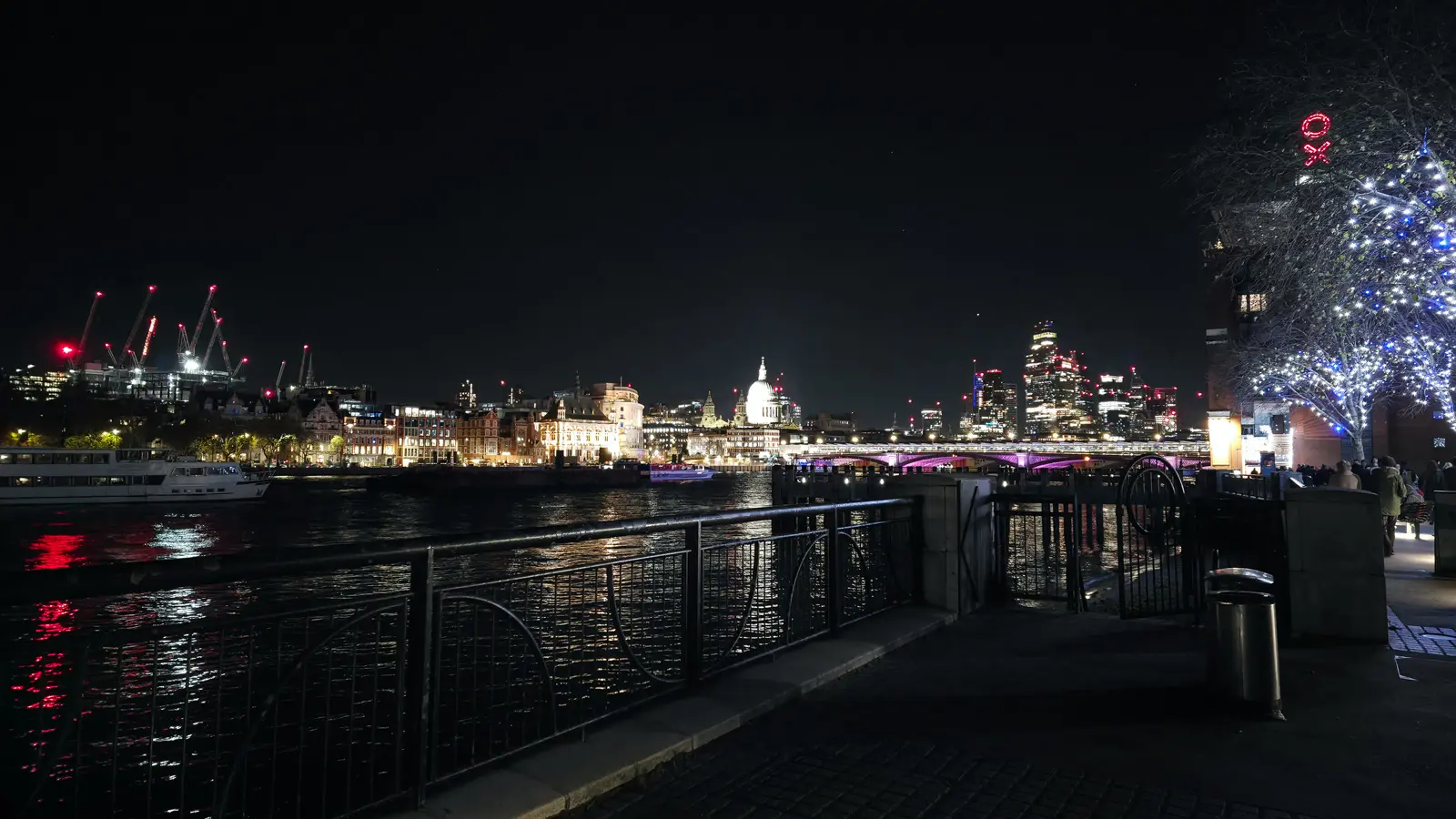 A night view east along the Thames to the floodlit dome of St Paul’s Cathedral and the City skyline, with the OXO Tower’s red letters glowing on the right
