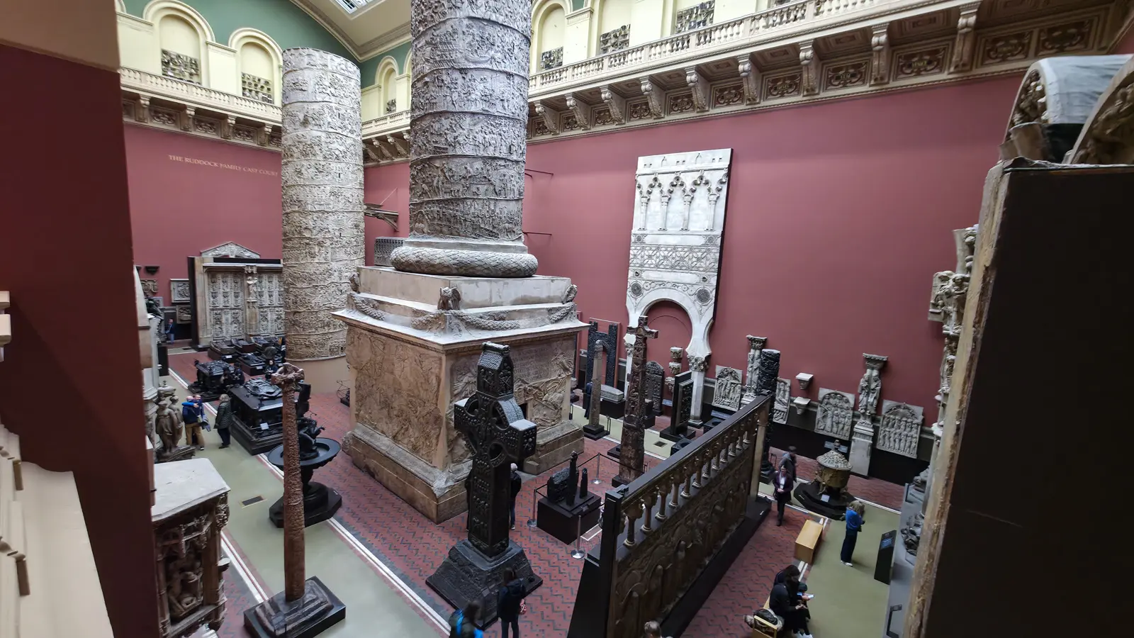 The plaster cast of Trajan's Column standing in two halves among other casts in the red-walled West Cast Court at the V&A, London