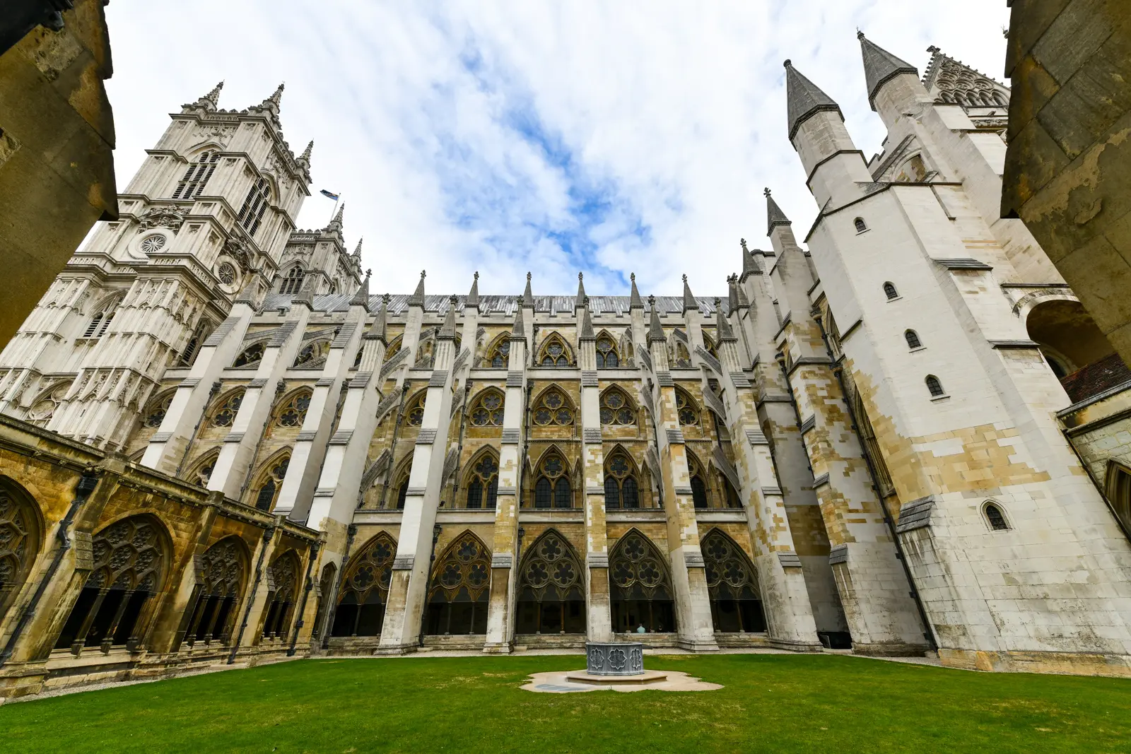 The Great Cloister of Westminster Abbey, a grassed quadrangle framed by Gothic arcades beneath the soaring church walls and a western tower
