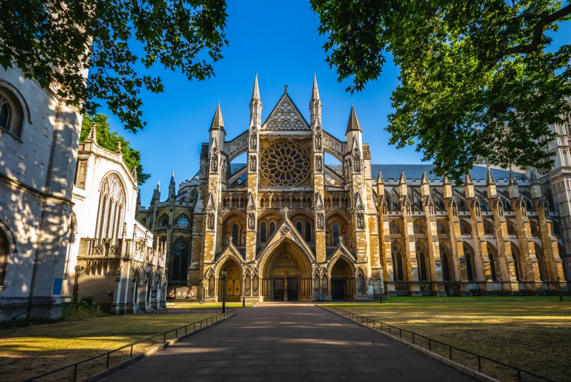 The symmetrical north front of Westminster Abbey with its great rose window above three carved Gothic doorways, a path leading up across the green