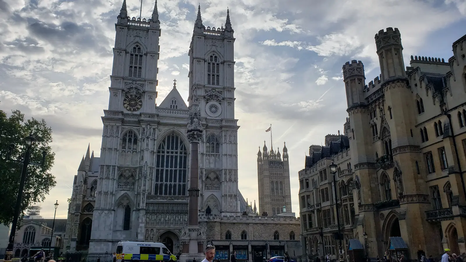 The west front of Westminster Abbey with its two pale Hawksmoor towers, a tall memorial column in front and the Victoria Tower of Parliament behind