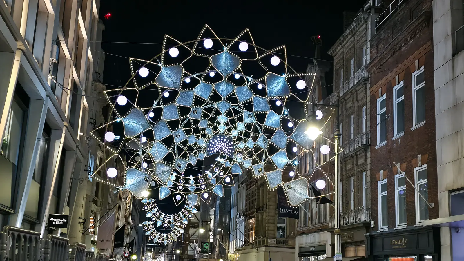 A starburst canopy of white lights strung over a side street off New Bond Street at Christmas, London