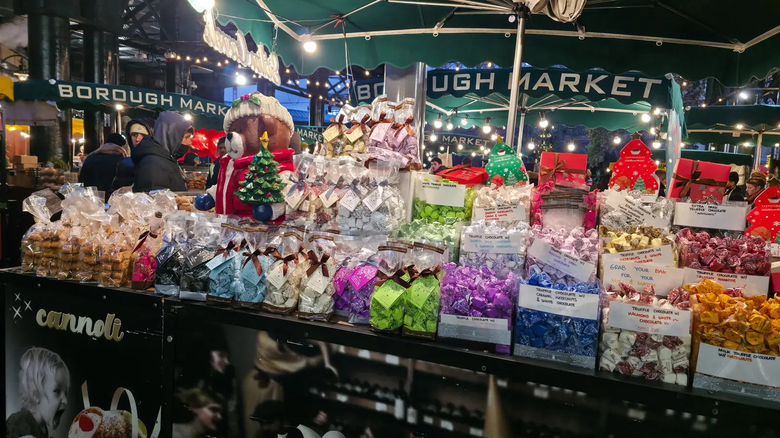 An Italian chocolate and cannoli stall dressed for Christmas under the Borough Market awning, London