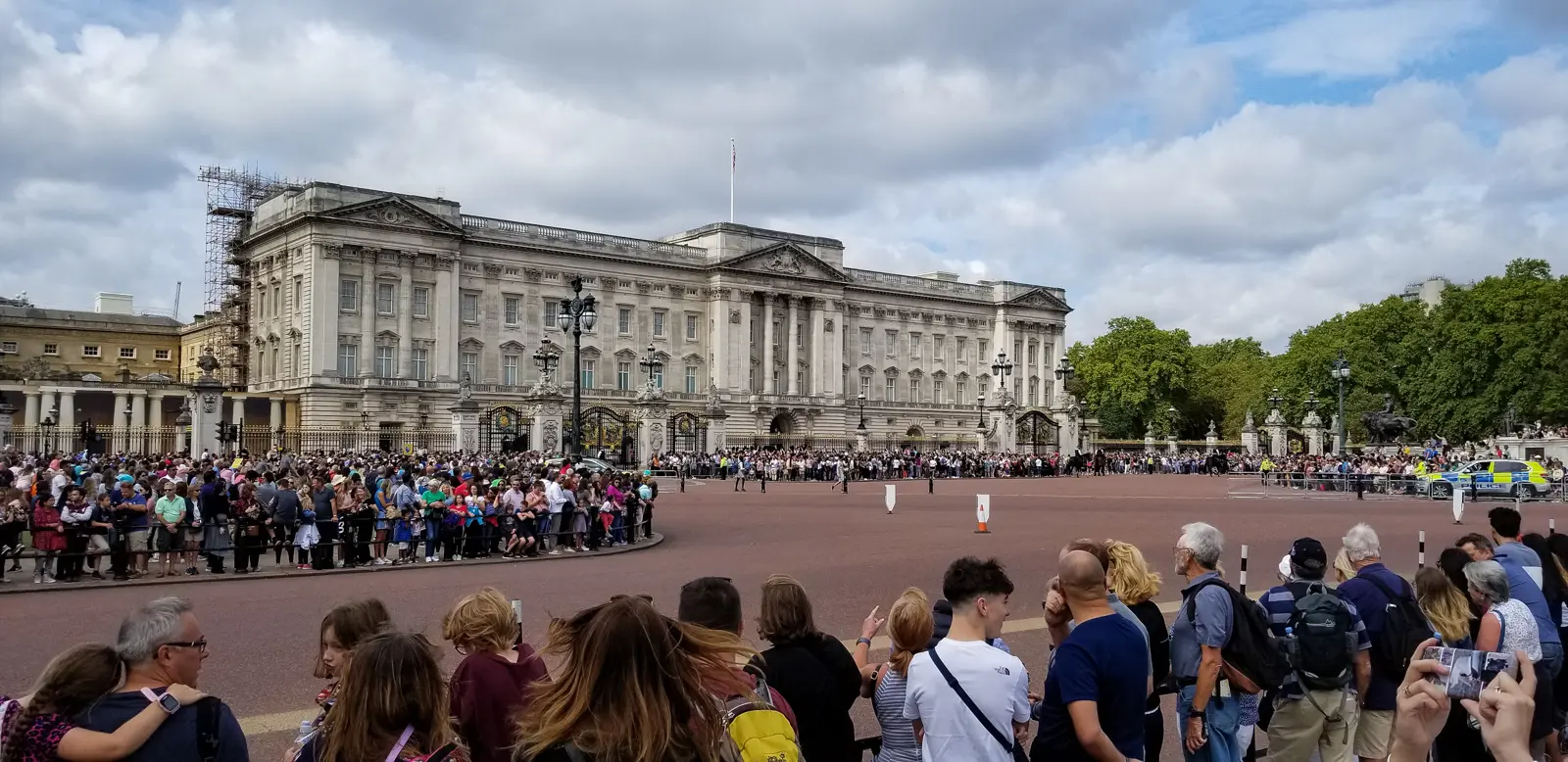 Buckingham Palace behind its gates, with a large crowd gathered outside for the Changing of the Guard, London