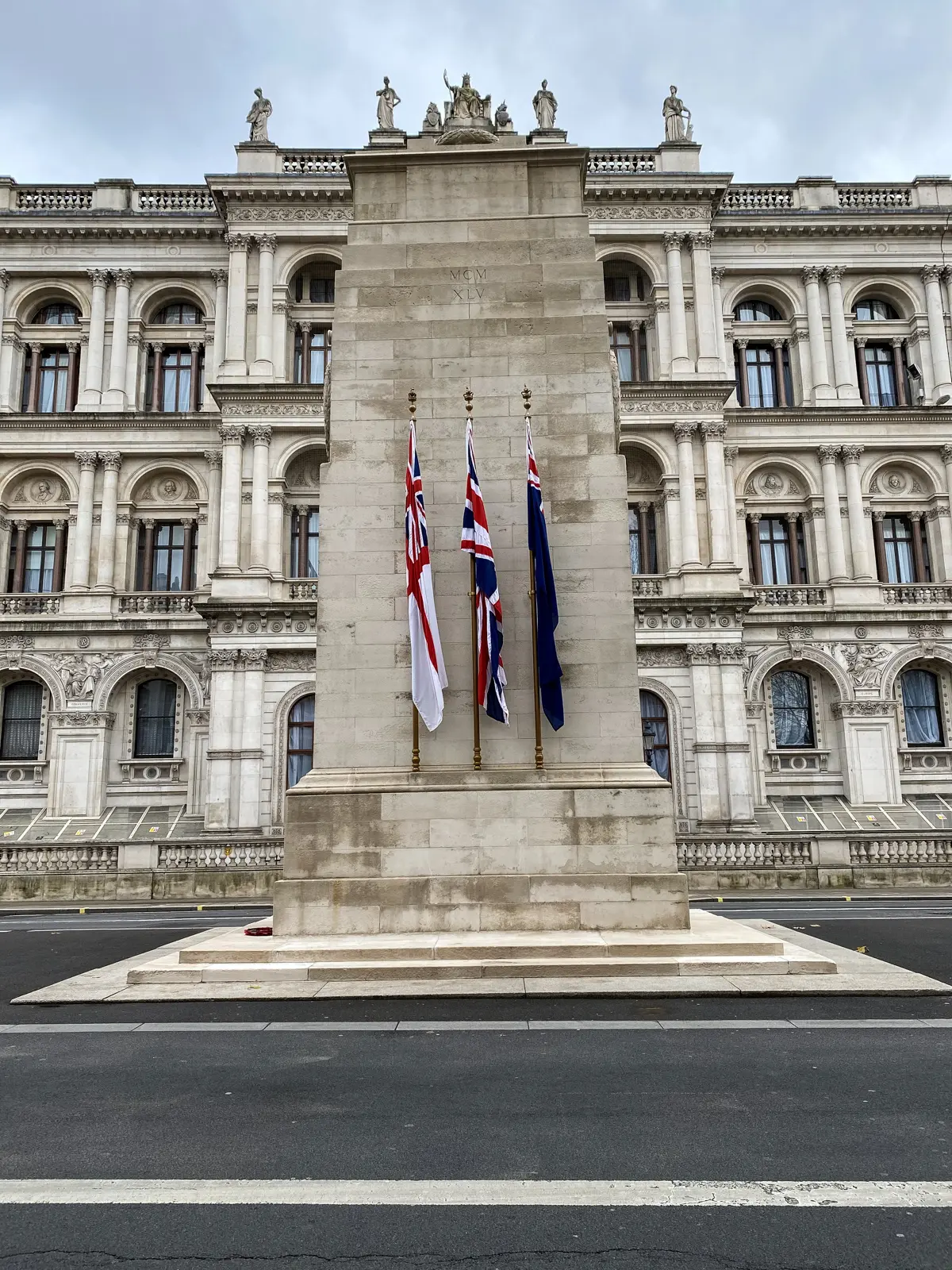 The Cenotaph war memorial in the middle of Whitehall, flags on its flanks, the Foreign Office behind, London