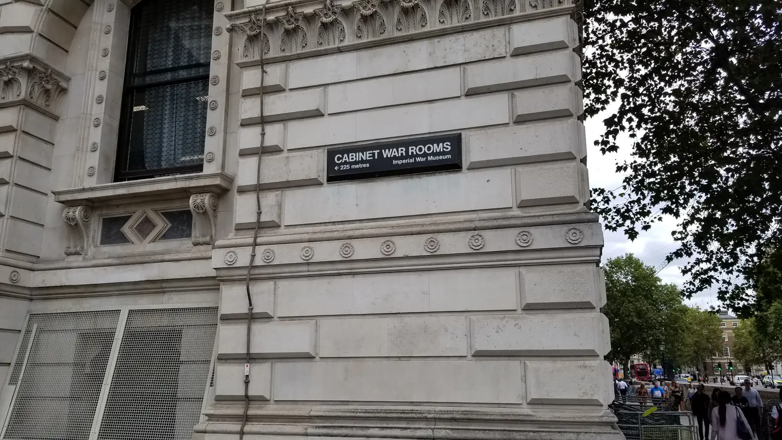 A wall sign reading Cabinet War Rooms, Imperial War Museum, 225 metres, on a Whitehall building, London