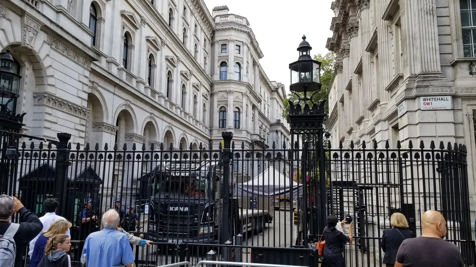 The black security gates at the Whitehall entrance to Downing Street, with the street sign for Whitehall SW1