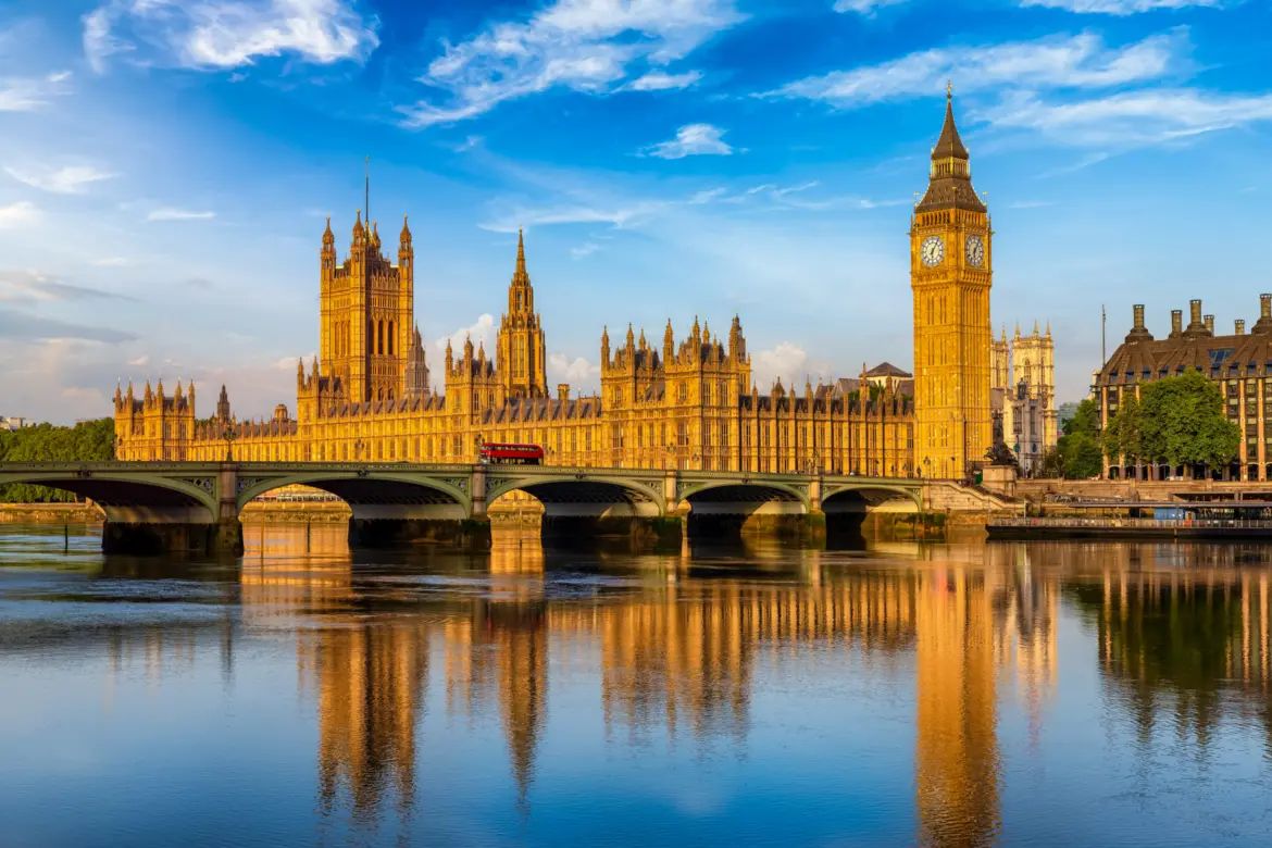 The Houses of Parliament and Big Ben in golden evening light beside Westminster Bridge and the River Thames, London