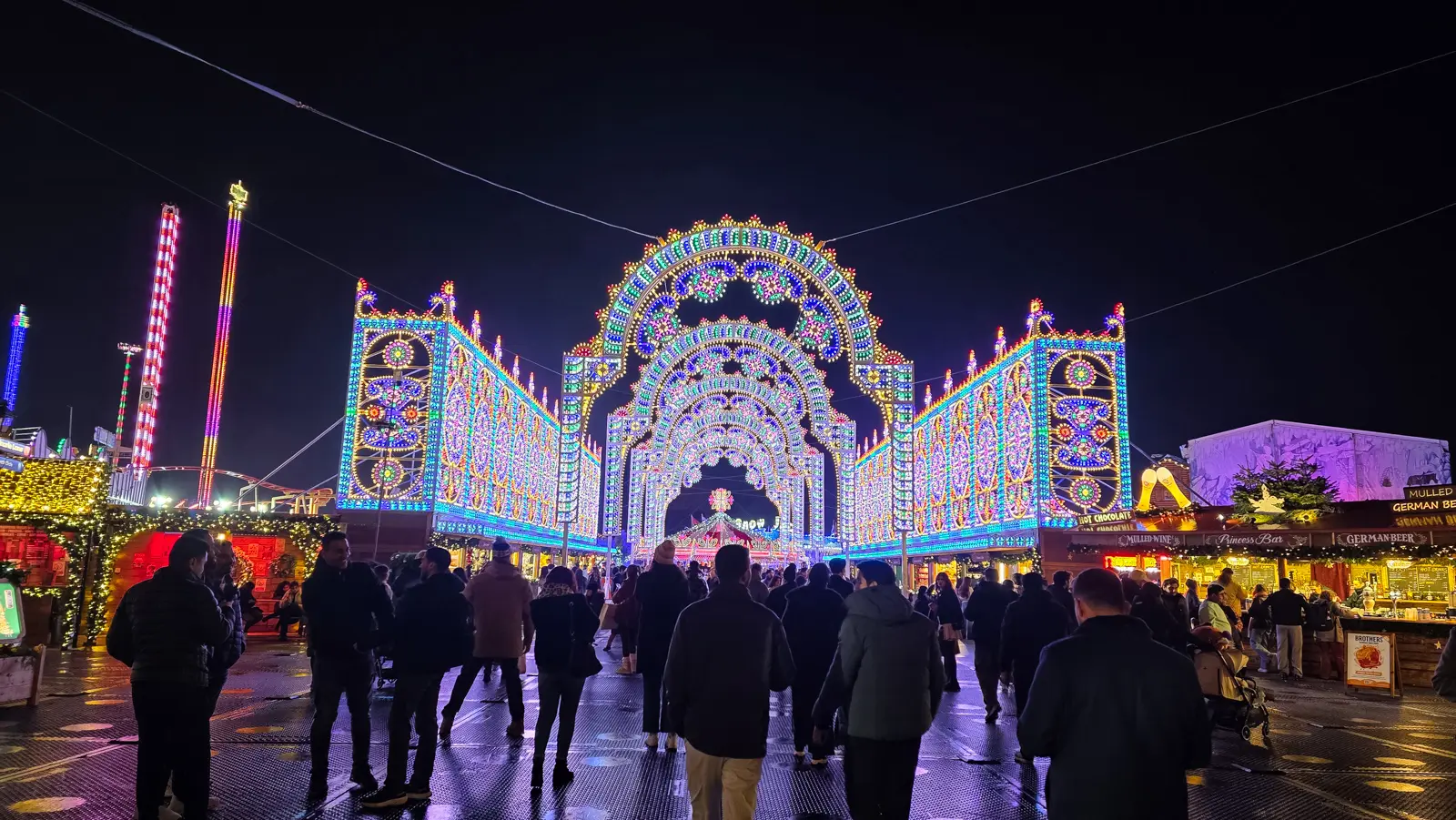 The illuminated entrance arch and market stalls at Hyde Park Winter Wonderland at night, London