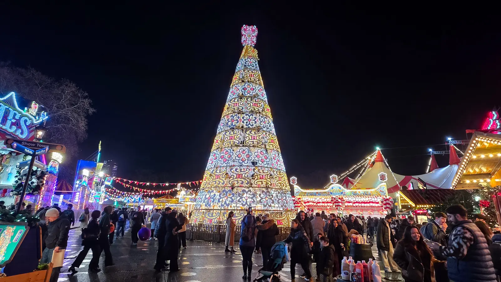 A towering cone of lights above the fairground rides and stalls at Hyde Park Winter Wonderland, London