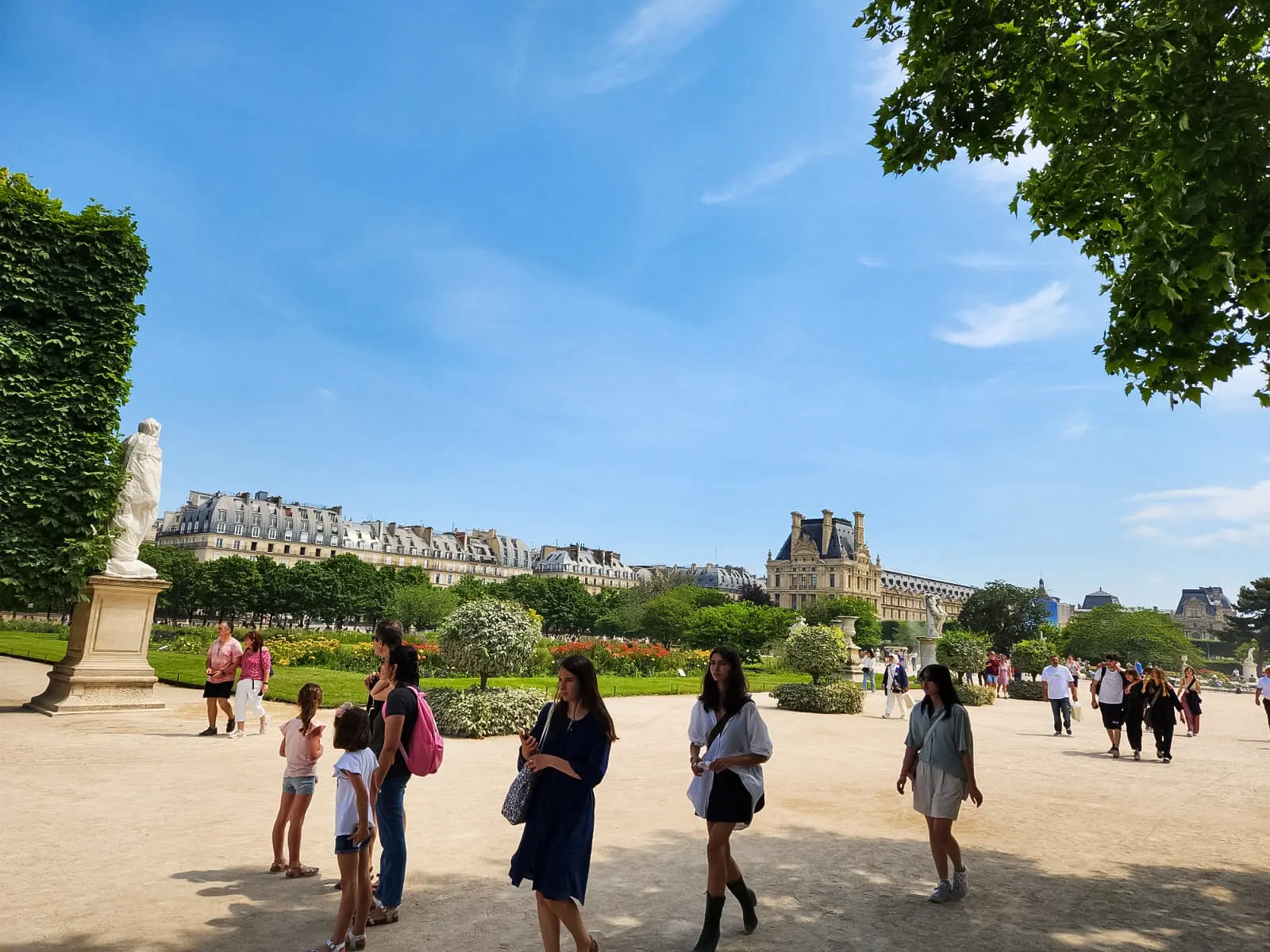 People strolling in the Jardin des Tuileries on a summer day, the Louvre behind, Paris
