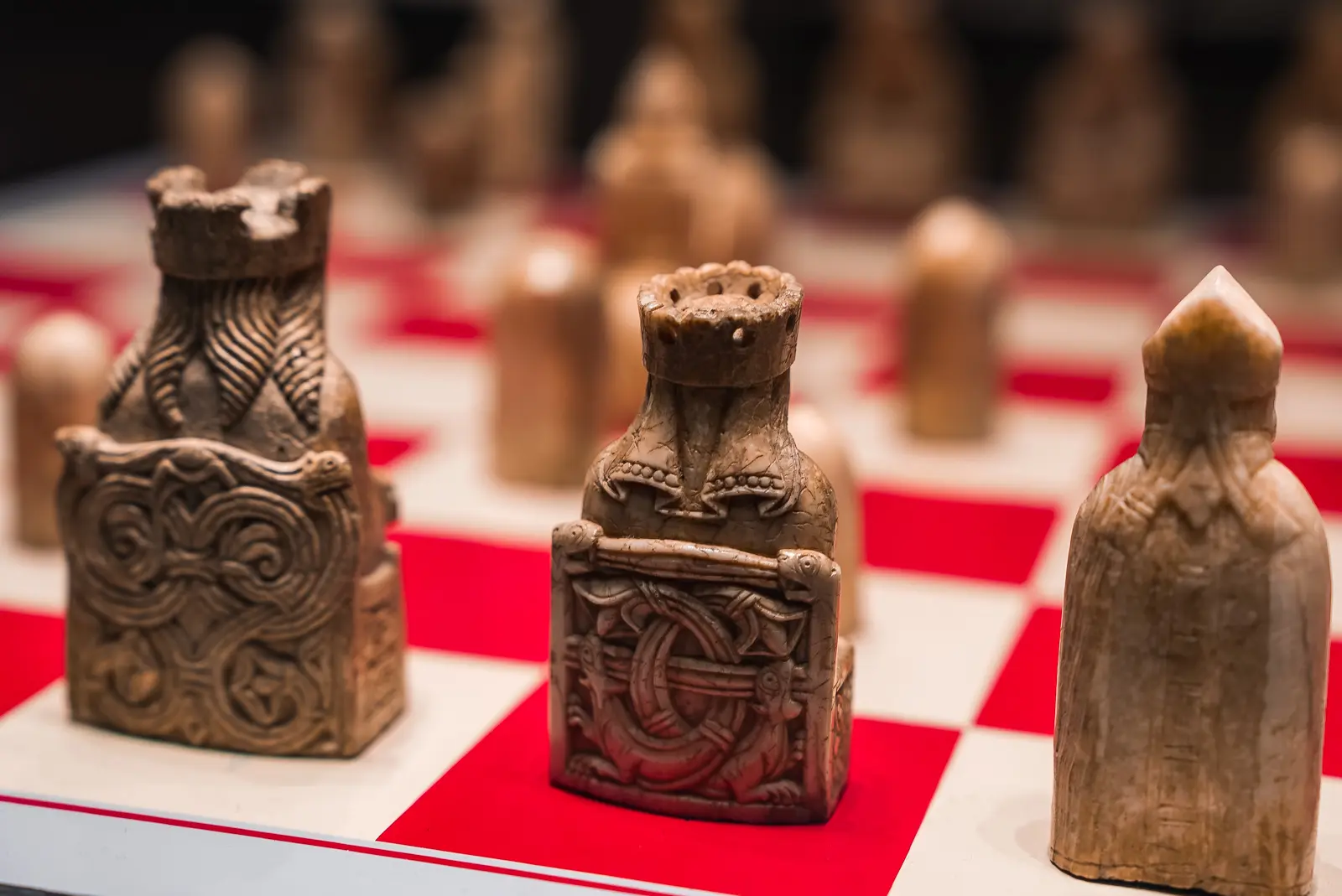 Lewis Chessmen close up on the red and white board, two seated figures on carved thrones beside a standing piece, British Museum