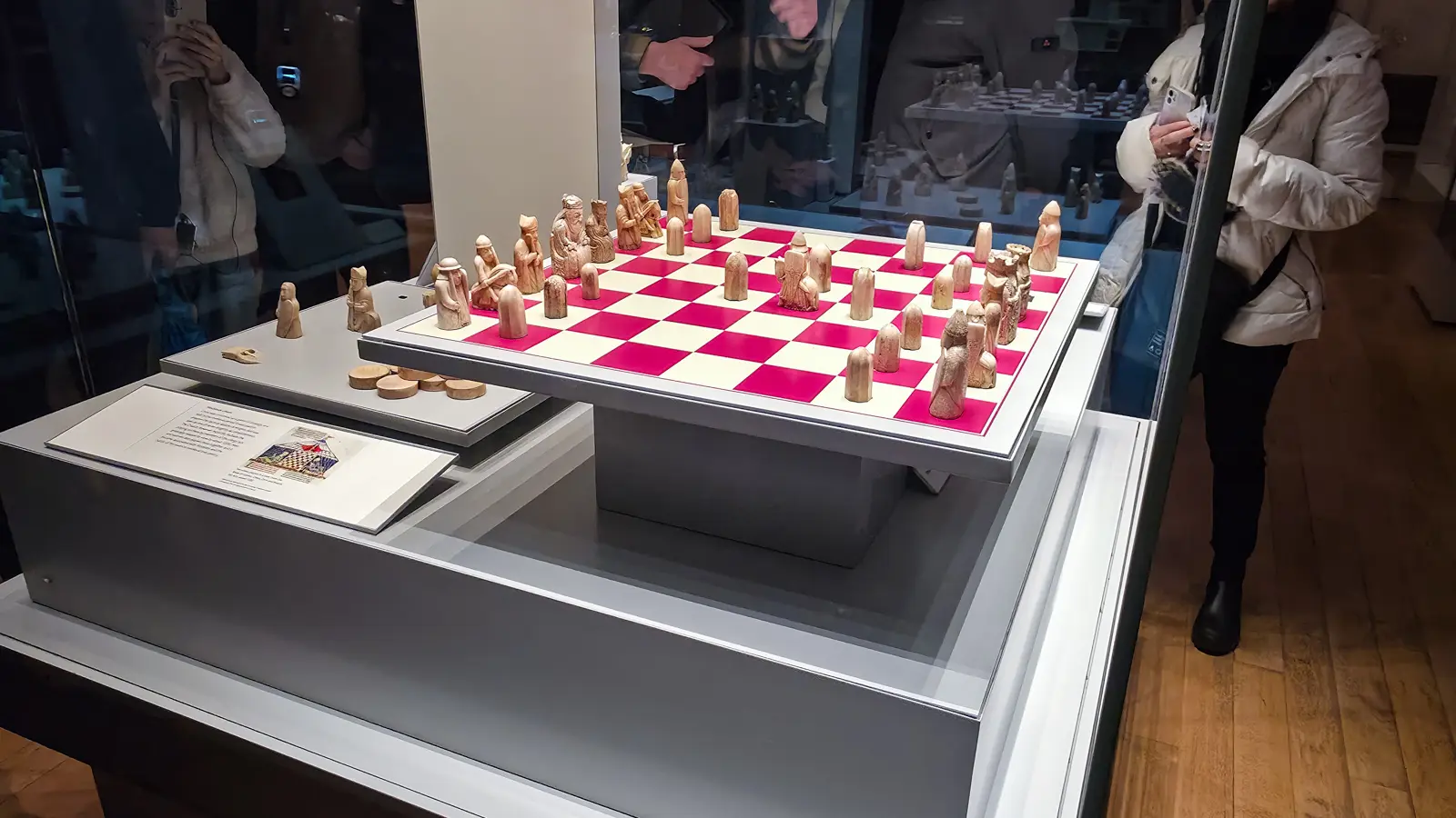 Visitors with phones crowd the glass around the Lewis Chessmen display, Room 40, British Museum, London