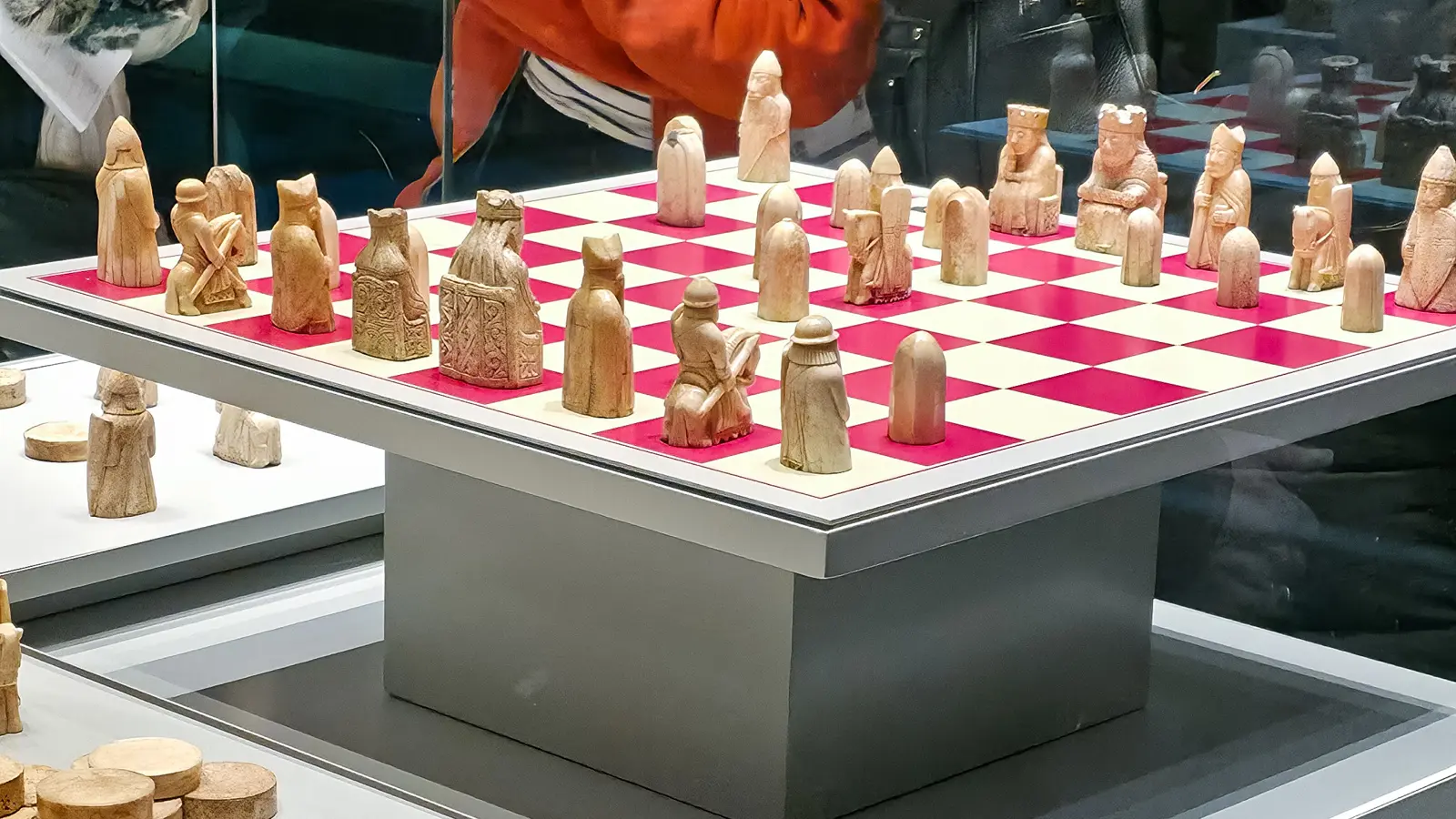 A visitor leans in to study the Lewis Chessmen on their board, Room 40, British Museum, London