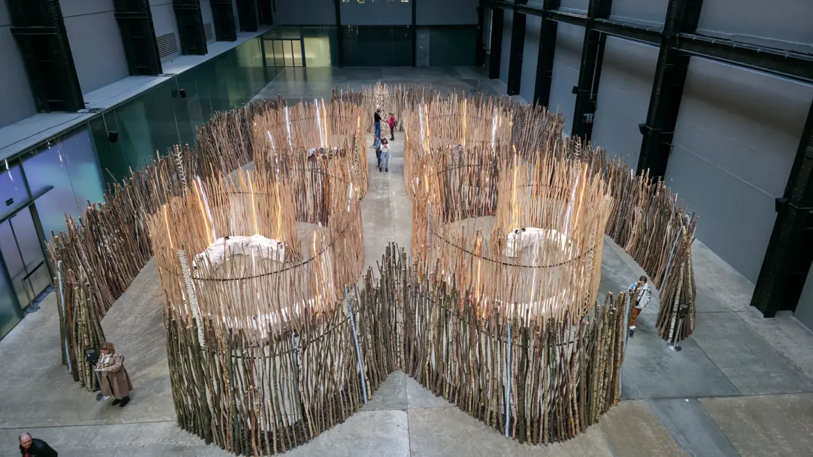 Máret Ánne Sara’s Turbine Hall installation at Tate Modern, circular enclosures of upright wooden poles lit from within