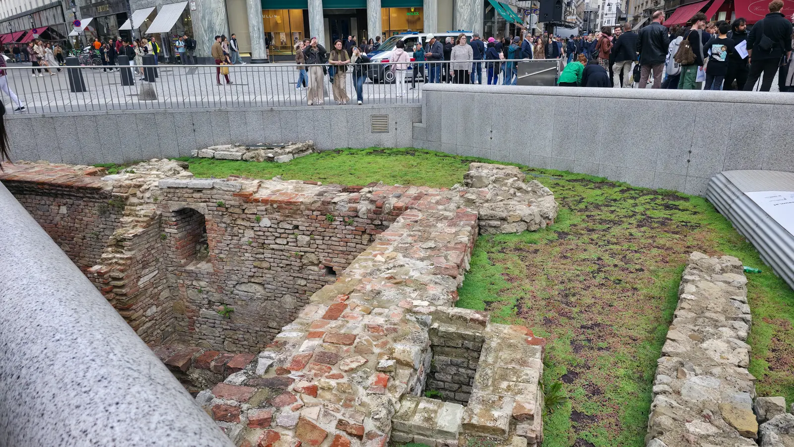 The sunken archaeological excavation in the middle of Michaelerplatz in Vienna, with shoppers at the railing above