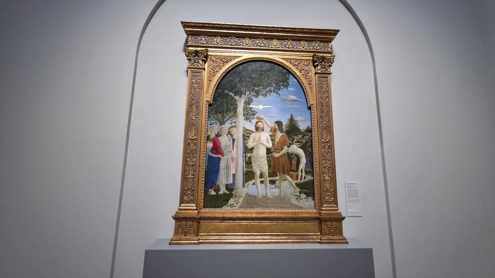 The Baptism of Christ by Piero della Francesca, Christ baptised by John the Baptist with a white dove above and three angels watching at the left, National Gallery, London.