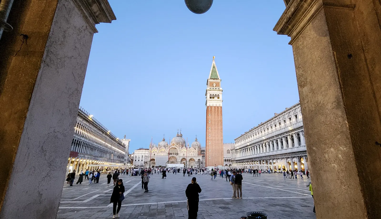 Piazza San Marco at dusk, seen through an arch of the arcade, the Campanile and Basilica ahead, Venice