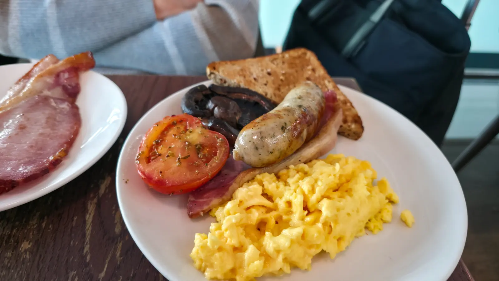 A cooked breakfast with scrambled eggs, sausage, bacon, grilled tomato, mushroom and toast at Plane Food Market, Heathrow