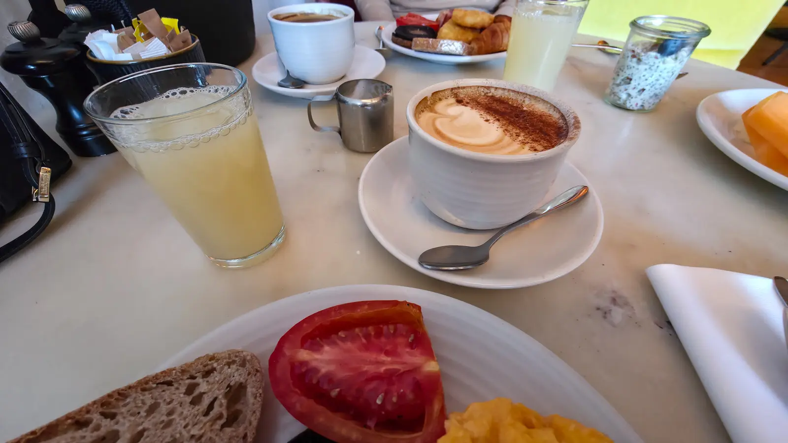 A cocoa-dusted cappuccino and a tall glass of apple juice on the marble table at Sea Containers Restaurant, South Bank London