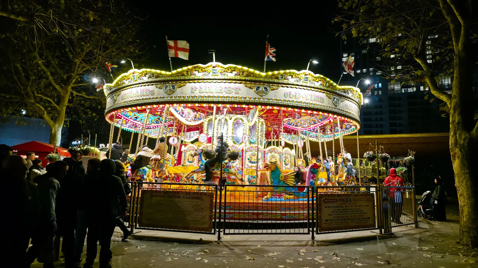 A vintage illuminated fairground carousel with painted horses at a South Bank Christmas market, London