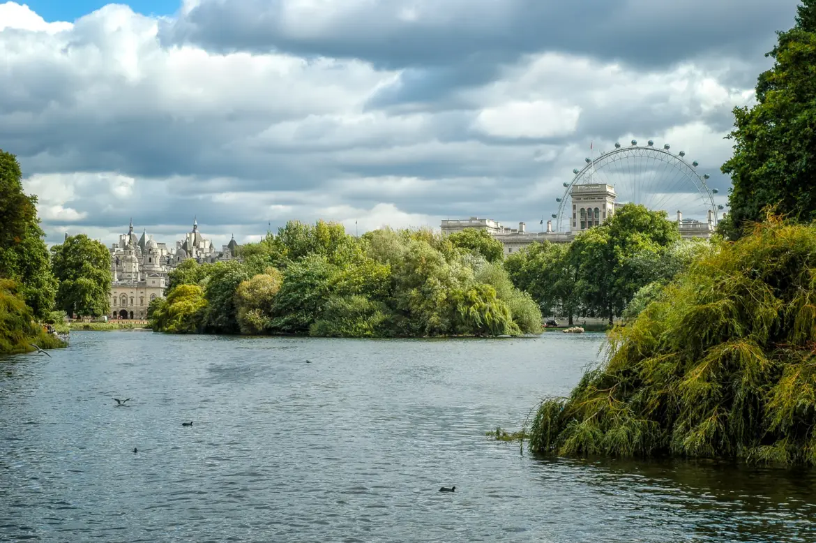 The classic eastward view across St James's Park Lake to the rooftops of Whitehall and the London Eye, with Duck Island's willows in the foreground.