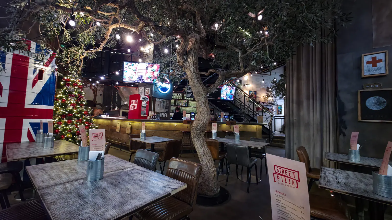 The interior of Street Pizza by Gordon Ramsay near St Paul’s, with an olive tree, festoon lights and a Union flag on the wall